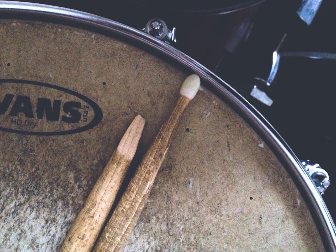 menu-02 Detailed shot of a broken drumstick resting on a textured snare drum head. Musical vibes.
