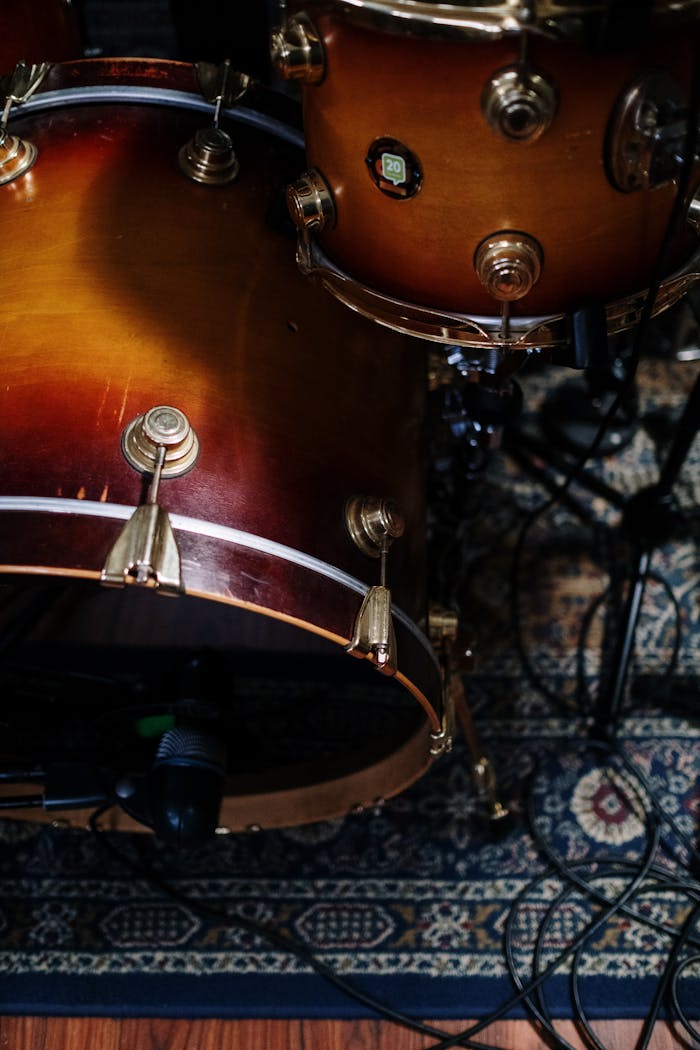High-angle view of a classic drum set with a rich wood finish on a patterned rug.